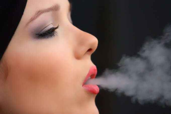 kobieta wydmuchująca dym
